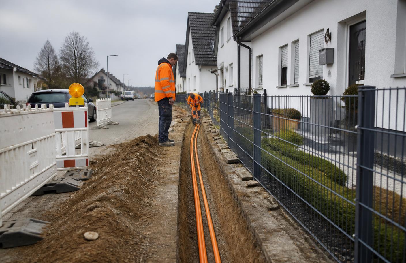 Glasfaser-Hausanschluss: offener Graben mit orangefarbenen Leerrohren in einer deutschen Wohnstraße